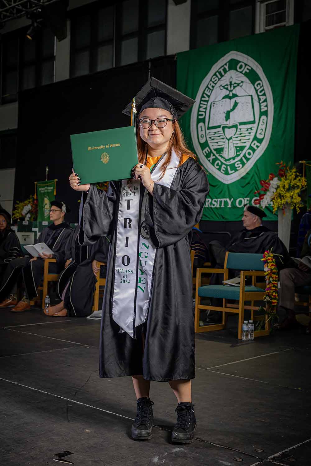 Photo of a woman in a graduation robe holding a degree